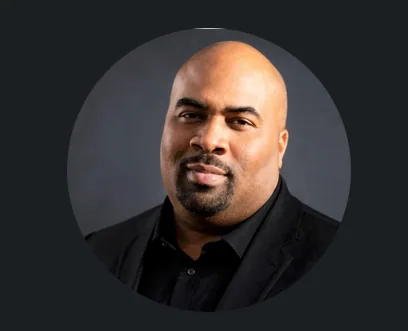 Todd Davis in a black suit against a dark gray circular background.